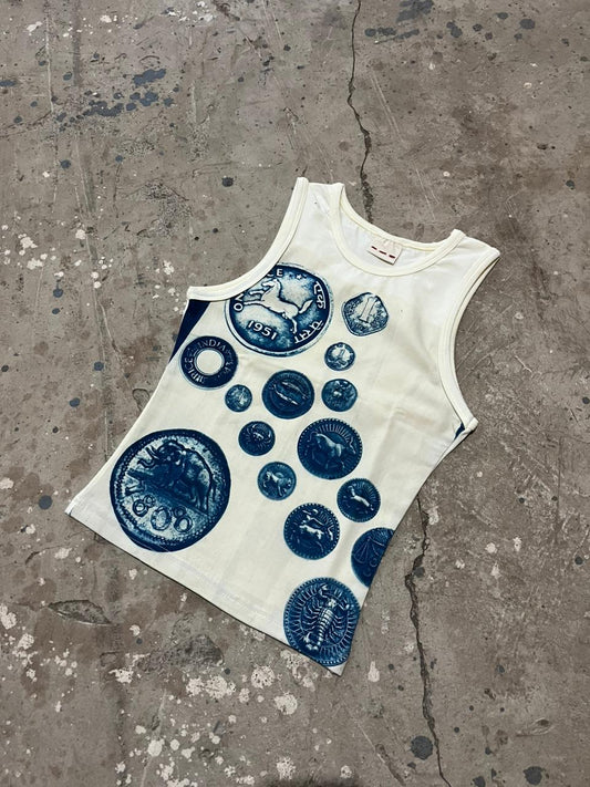 White tank top with blue circular designs on a concrete surface, old coinage print, sun printed top, art piece, wearable art 